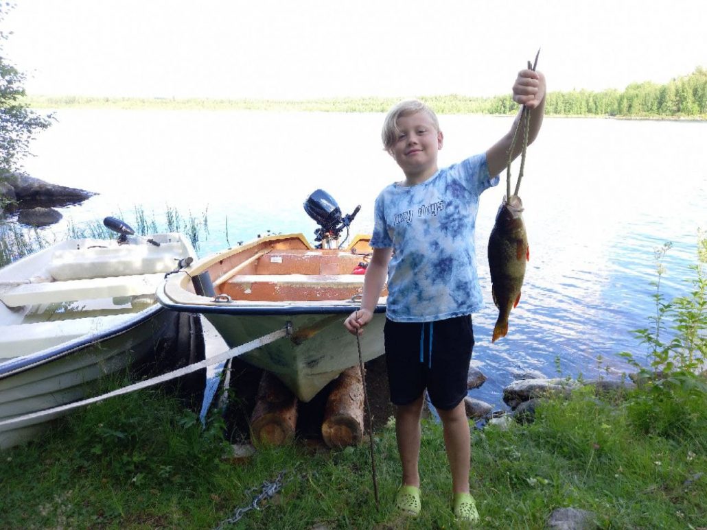 Jongen pronkt met visvangst bij de rivier